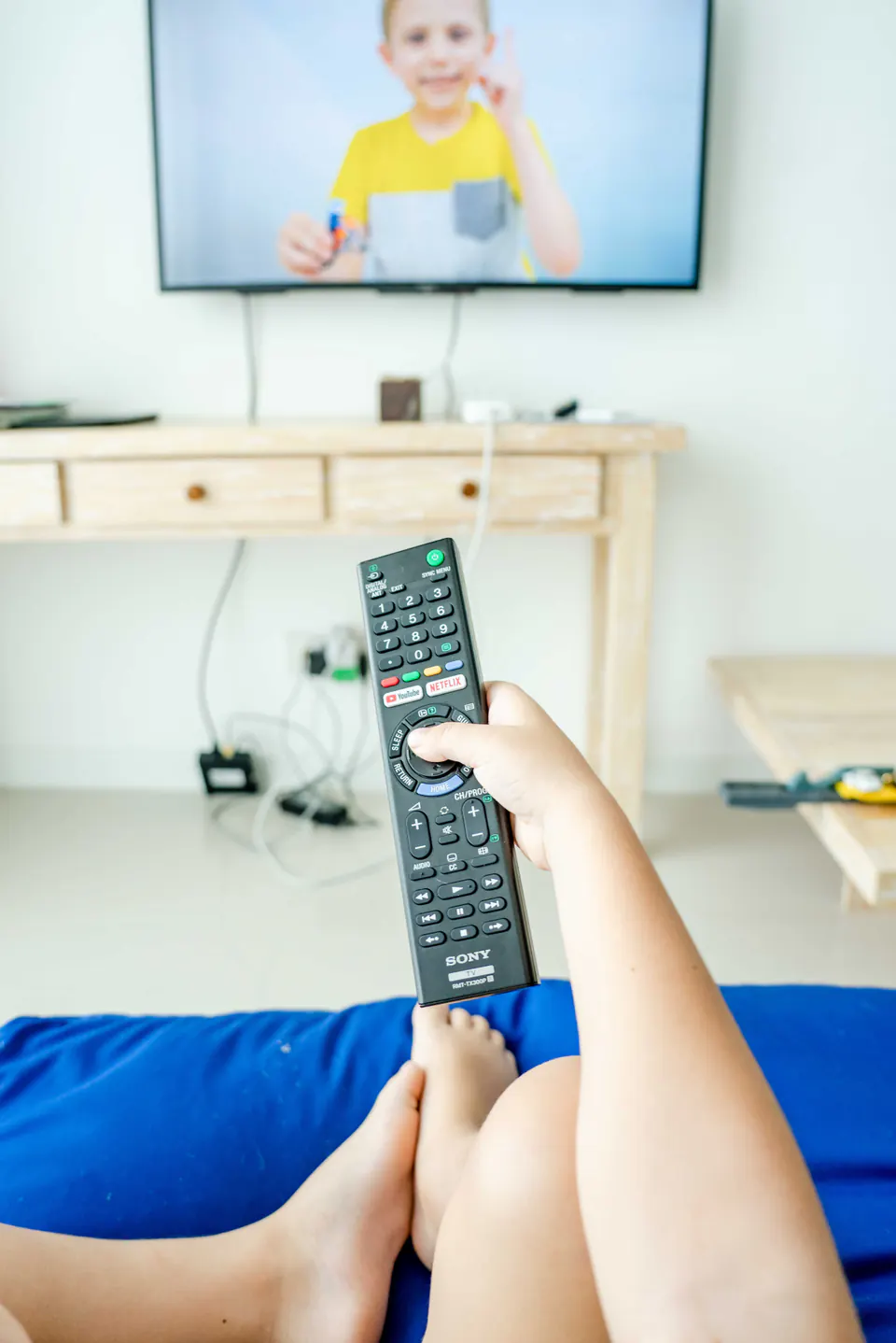 A person holding a remote control while watching television.