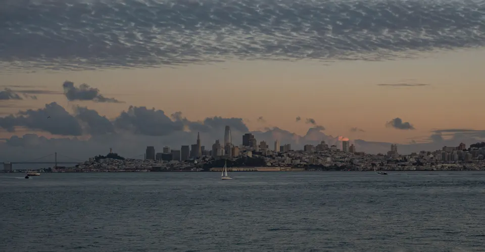The San Francisco skyline at sunset, seen across the water.