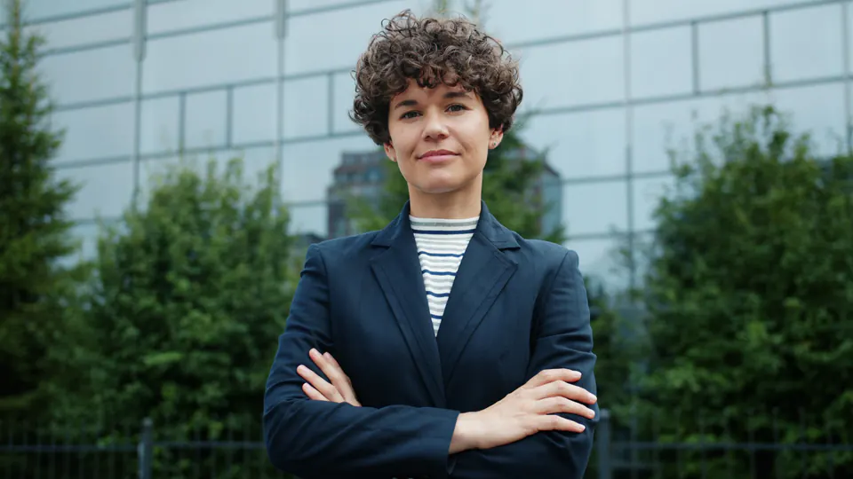 A confident young professional standing in a city street.