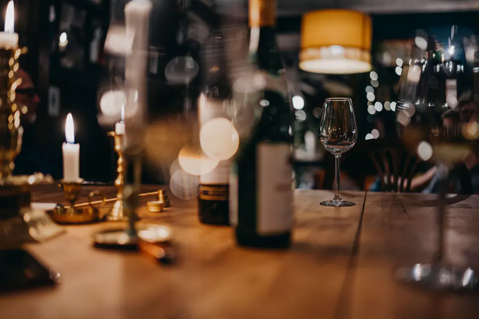Candles, wine glasses and a bottle on a restaurant table.