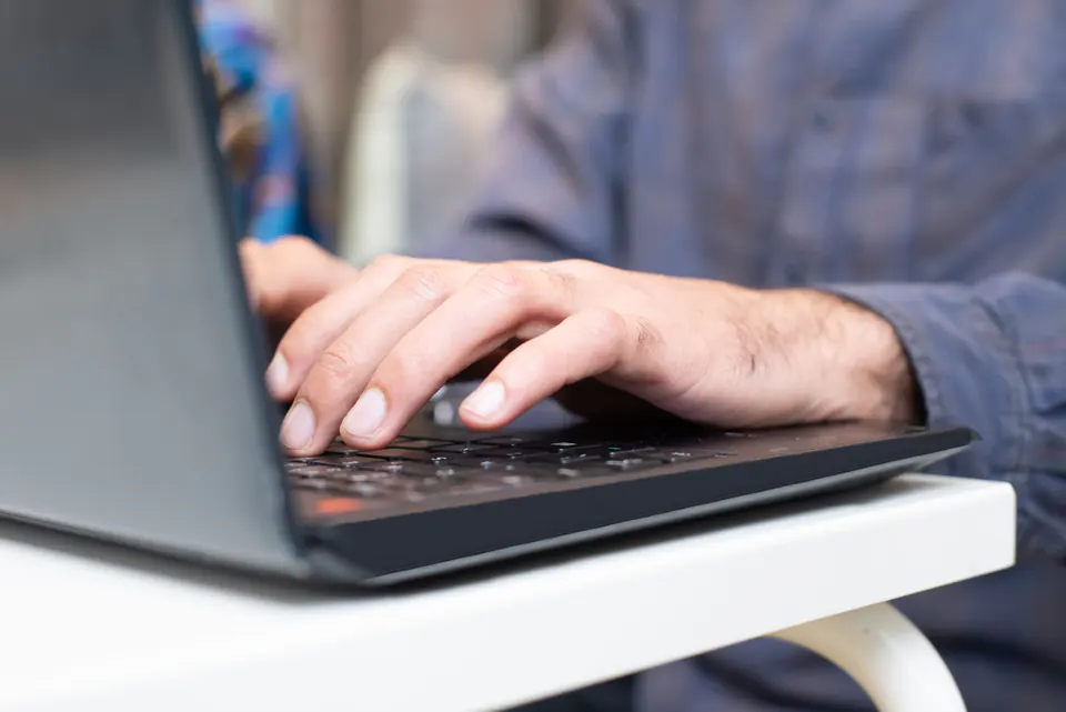 Close-up of hands typing on a laptop keyboard.