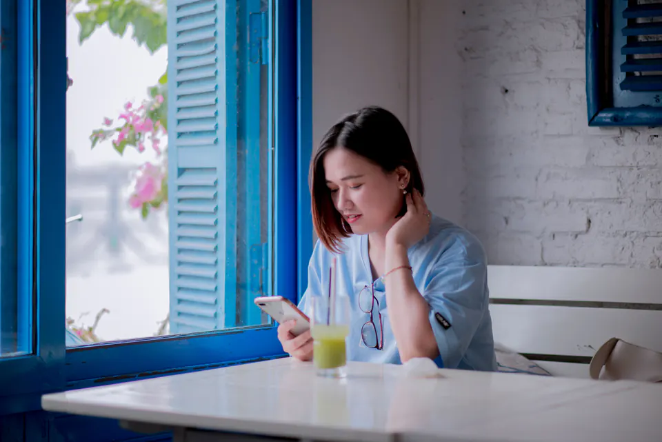 A woman checking her smartphone at a cafe table.